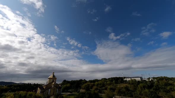 Time lapse: the sun hidden behind fluffy clouds flying in the sky. alt