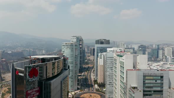 Forward Fly Above Street Leading Between Rows of Tall Office Buildings alt
