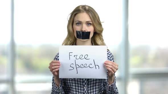 Portrait of Young Woman with Taped Mouth and Banner with Free Speech Text alt