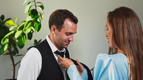 Wife Tying Tie on Husband's Shirt Before Work at Home in Living Room