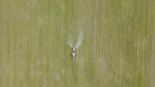 Aerial View of a Tractor Which Spraying Chemical Insecticide or Fertilizers to Orchard Trees alt