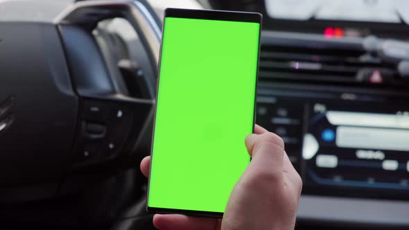 Close Up Hand of the Driver in Car Uses a Smartphone with a Green Screen Inside a Car alt