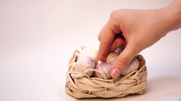 Garlic in a Wicker Basket, on a White Background. Dried French Garlic. Red Garlic. alt