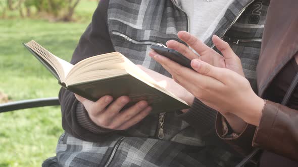 Beautiful Couple Sitting On A Bench In The Park In The Spring And Reading An Interesting Book alt