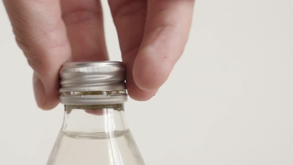 Unscrewing metal cap from glass bottle 4K video