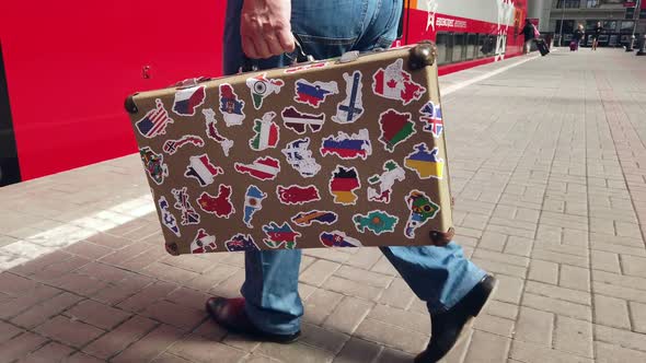 the Passenger Is on the Platform of the Station with a Suitcase with Stickers From Different