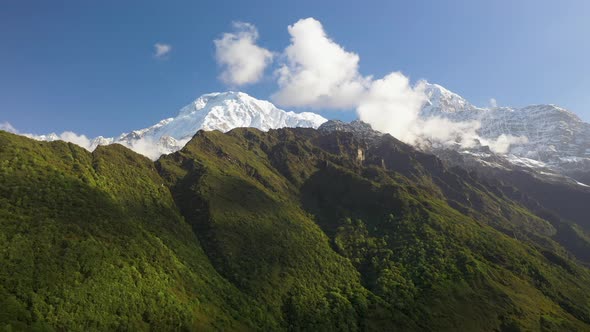 Epic aerial drone shot of the sun shining on a mountain face and snowy peak in the Annapurna mountai alt