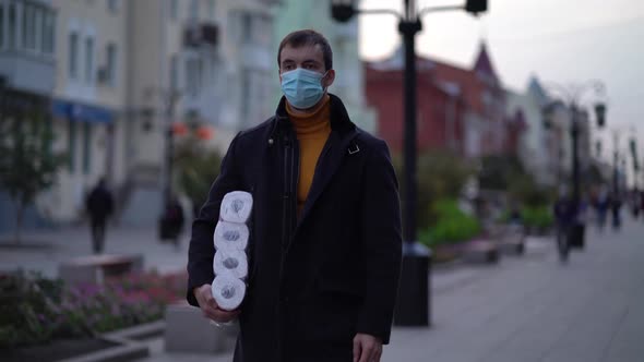 Men Walking in Medical Mask with Toilet Paper During the Second Wave Quarantine Coronavirus COVID-19 alt