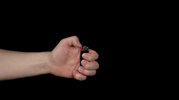 A Man Lights a Lighter. A Man Holds a Lighter in His Hand and Spins a Drum on a Black Background alt