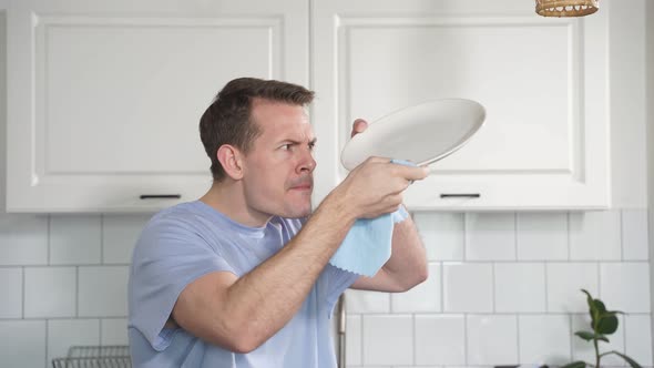 Attractive Young Caucasian Man Washing Dishes at Kitchen Sink While Doing Cleaning at Home at