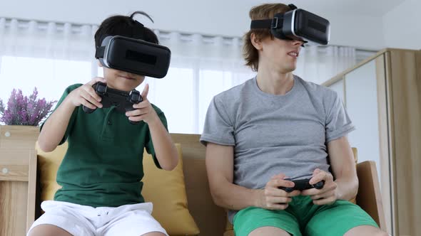 Funny father and son enjoying video games wearing VR headsets at home. alt