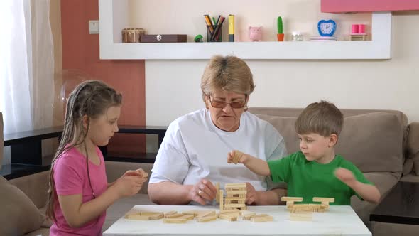 Grandma Plays with Children with Wooden Blocks in the Room. Social Distancing and Self-isolation in
