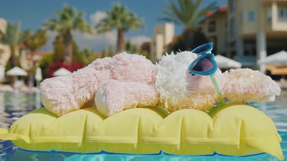 A Plush Bunny Floats on a Yellow Inflatable Mattress in the Pool. Rest with Children alt