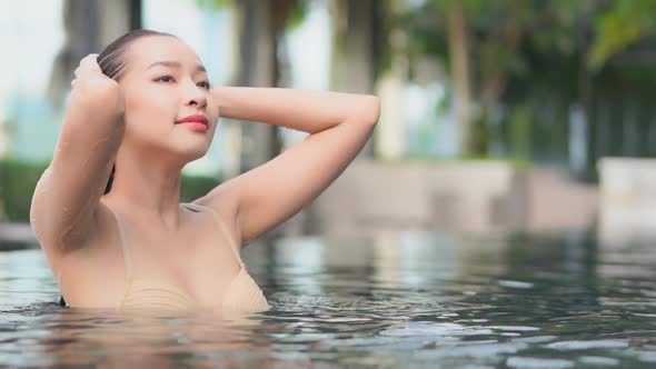 Young asian woman enjoy around outdoor swimming pool for leisure alt