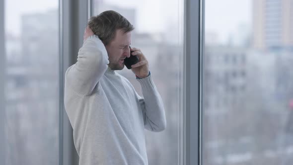 Confident Man Talking on the Phone Standing at Window in Office Hanging Up and Making Victory alt