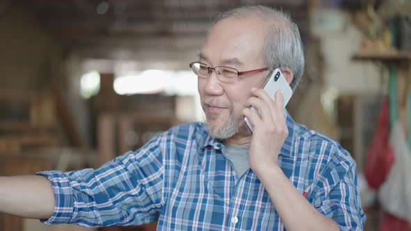 Asian senior shop owner talking to customer on the phone