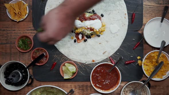 Overhead View of Adding Ingredients To Tortilla and Making a Burrito alt