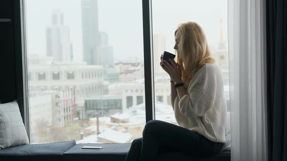 slender woman resting on the window sill with a view of the house