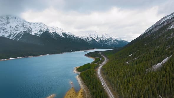 Aerial video showing forest on mountain slopes and road near Spray Lakes Reservoir, Alberta, Canada alt