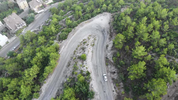 Aerial view of cars driving on curved, zigzag road or street on mountain hill with green natural  alt