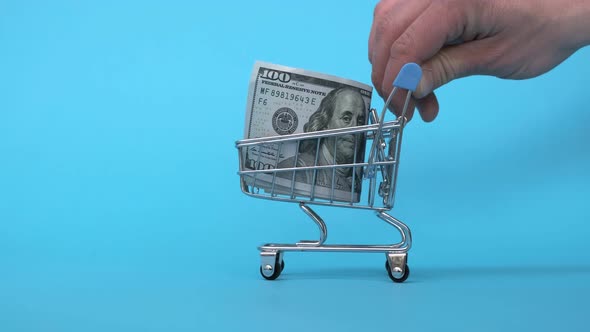Shopping Cart with One Hundred Dollar Banknote on Blue Background Buying Currency