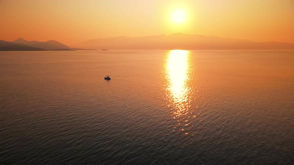 Sunset on the Ionian Sea coast, Greece. Bright Sun, land in the distance, floating boat alt