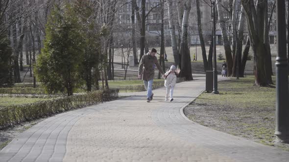 Joyful Caucasian Father and Daughter Jumping and Running Along the Alley in Park and Leaving. Happy alt