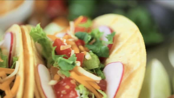 Ground beef tacos with romaine lettuce, diced tomatoes, radishes, and shredded cheddar cheese. alt