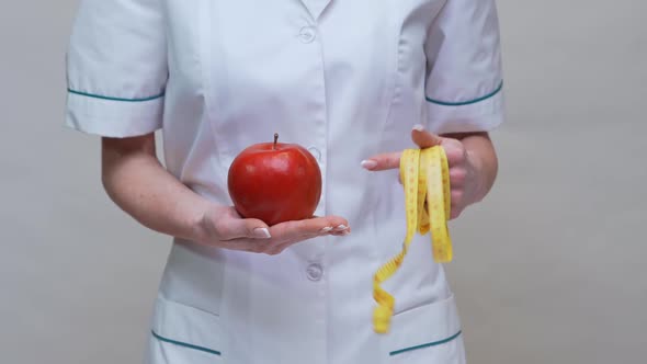 Nutritionist Doctor Healthy Lifestyle Concept - Holding Organic Red Apple and Measuring Tape alt