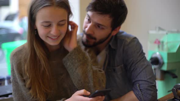 Couple looking at smartphone together in coffee shop