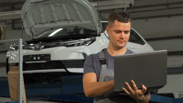 Car Mechanic Smiling Showing Thumbs Up While Working on the Laptop alt
