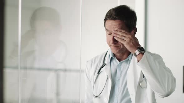 Mature Adult Male Doctor in Hospital looking out of window