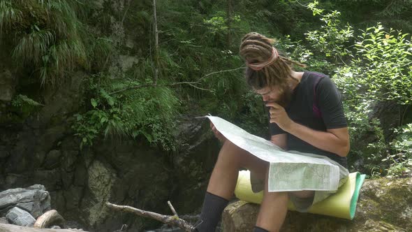 Traveler Considers Map in Forest