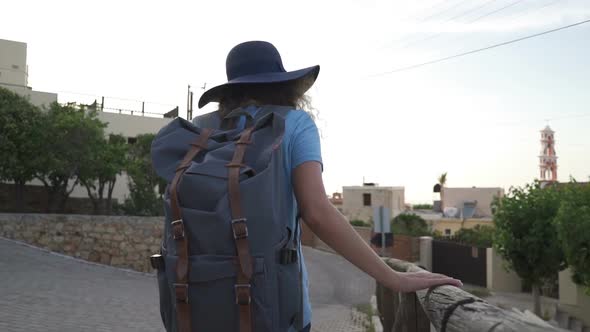 The Camera Follows a Woman with a Backpack Walking in the Old City of Greece
