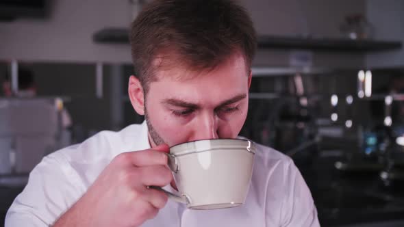 young man works at a laptop and drinks coffee alt