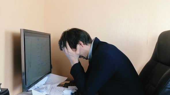 Confused Man Working at the Computer. Desperate Tears Paper and Throws It Around.