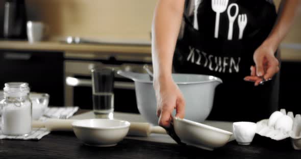 Woman in an Apron Pours Flour Into a Gray Bowl in a Modern Kitchen