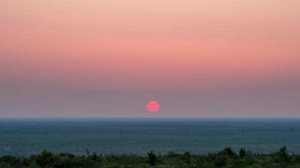 Red sun rising over the horizon in the steppe alt