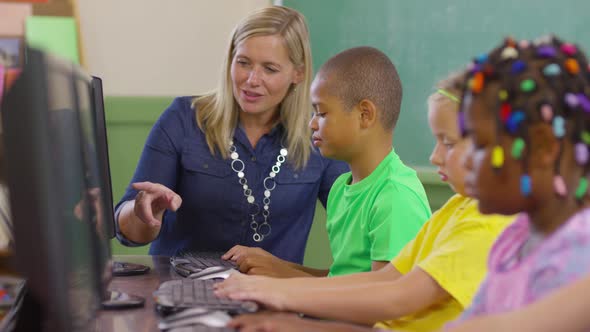 Teacher and student working on computers in school classroom alt
