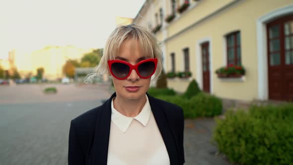 A Businesswoman in Red Glasses Walking Through the City Centre to Work