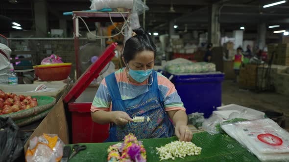 Thai Salesperson Creating A Jasmine Garland Inside The Pak Khlong Talat (Flower Market) In Bangkok alt
