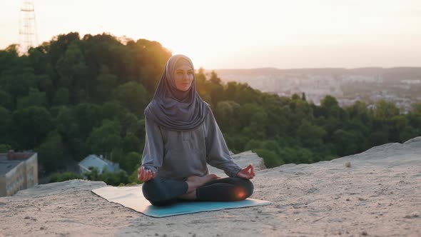 Portrait of Beautiful Yoga Woman in Hijab on Top of the Hill in the Evening