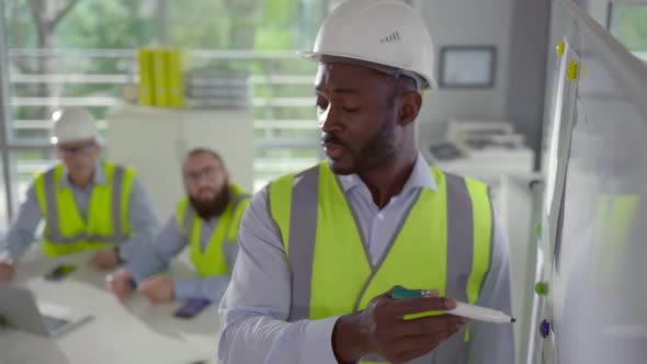 Close Up of Mixedrace Industrial Technician Draw on Whiteboard Having Meeting with Colleagues alt
