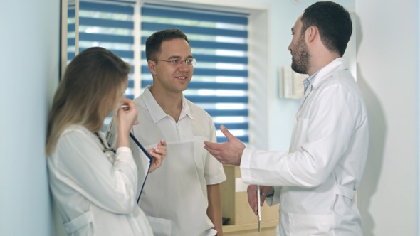 Male doctor holding tablet talking to two others doctors