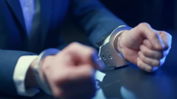 Arrested Criminal Businessman in Handcuffs in the Interrogation Room alt
