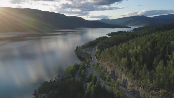 Flying Over Road with Cars and Kroderen Lake Shore in Norway at Sunset. Aerial Reveal Shot alt