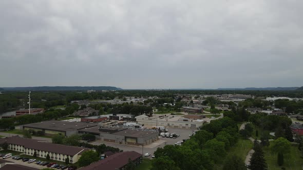 Aerial view of edge of city with apartments and business buildings surrounded by trees and park.