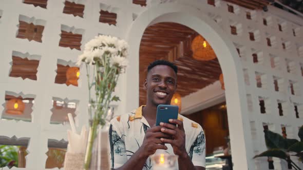 Young AfricanAmerican Man Uses Smartphone Outdoors alt