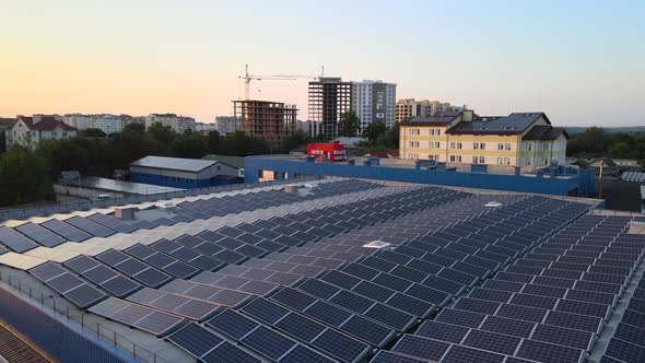 Aerial View of Blue Photovoltaic Solar Panels Mounted on Industrial Building Roof for Producing alt