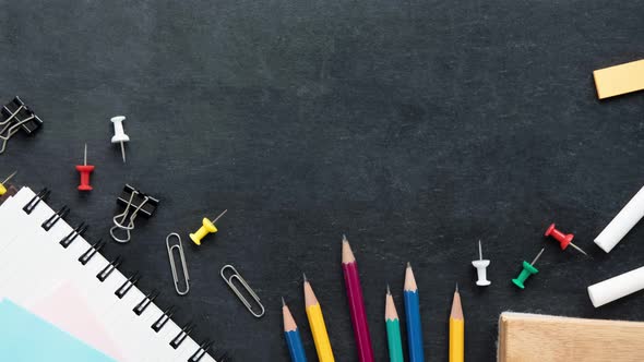 Top view of colorful stationery on blackboard background with copy space
